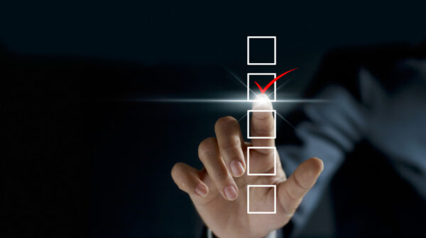 businessman checking mark on checklist with a red marker on dark background