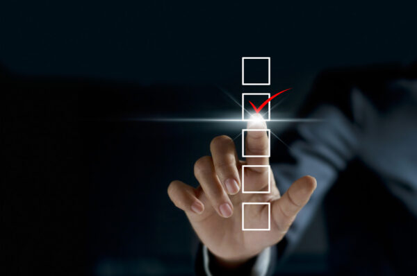 businessman checking mark on checklist with a red marker on dark background